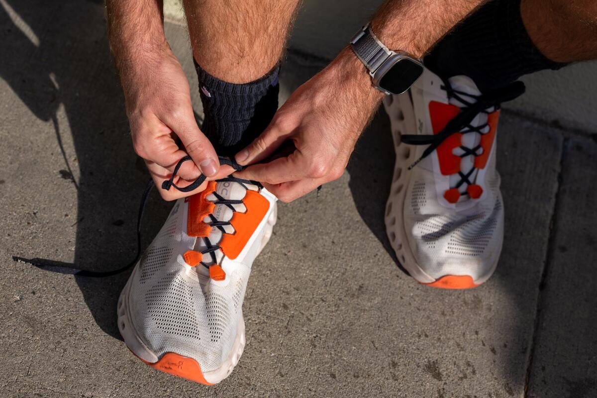 A close-up photo of someone tying the laces on their running shoes.