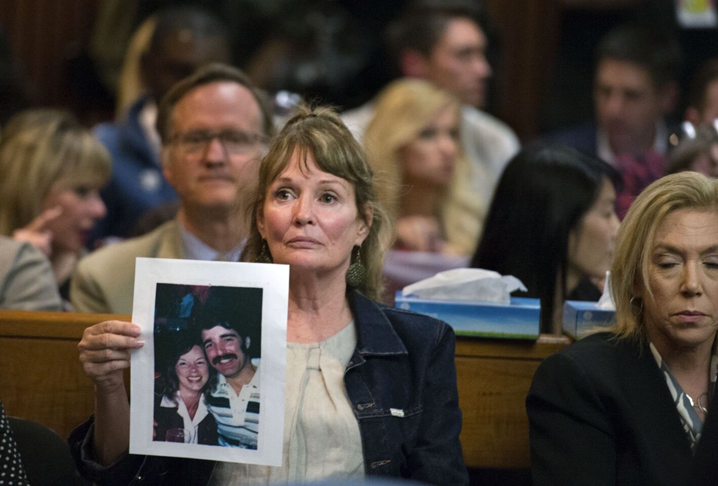 A woman holds up a photo of a couple in court.