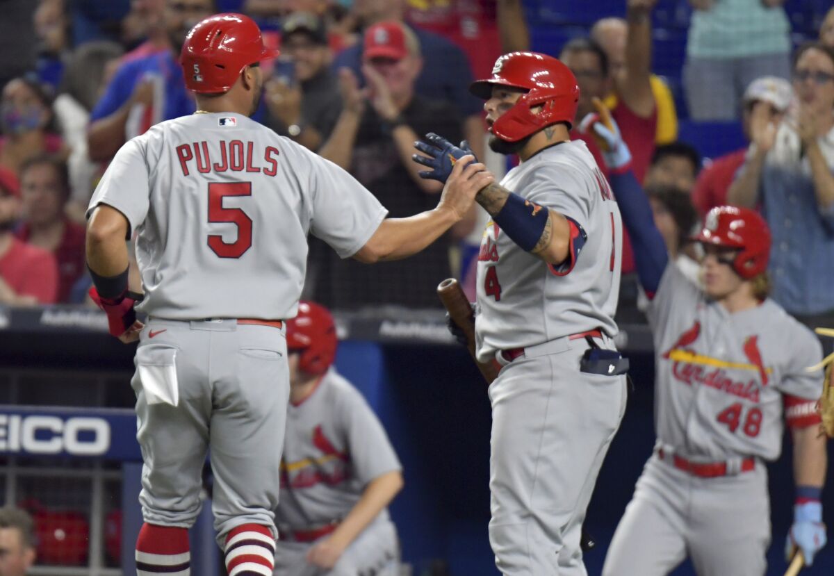 St. Louis Cardinals' Albert Pujols (5) is greeted by Yadier Molina after scoring during the second inning of the team's baseball game against the Miami Marlins, Tuesday, April 19, 2022, in Miami. (AP Photo/Jim Rassol)