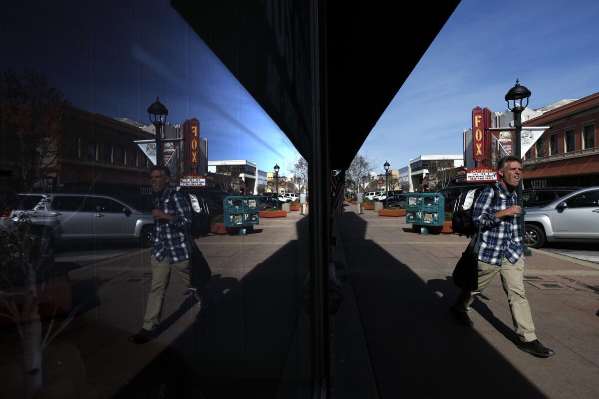A pedestrian is reflected in a storefront window as he walks down Main Street in the Old Town section of Salinas, Calif. City officials are hoping that the recent opening of Taylor Farms' $40-million headquarters will help revive downtown.
