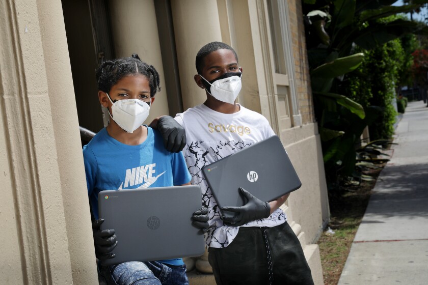 At the Watts Civic Center on Thursday, brothers Noah, 9, left, and Evan, 12, hold laptops purchased for them by a local prosecutor who connected with the boys at a community event. 