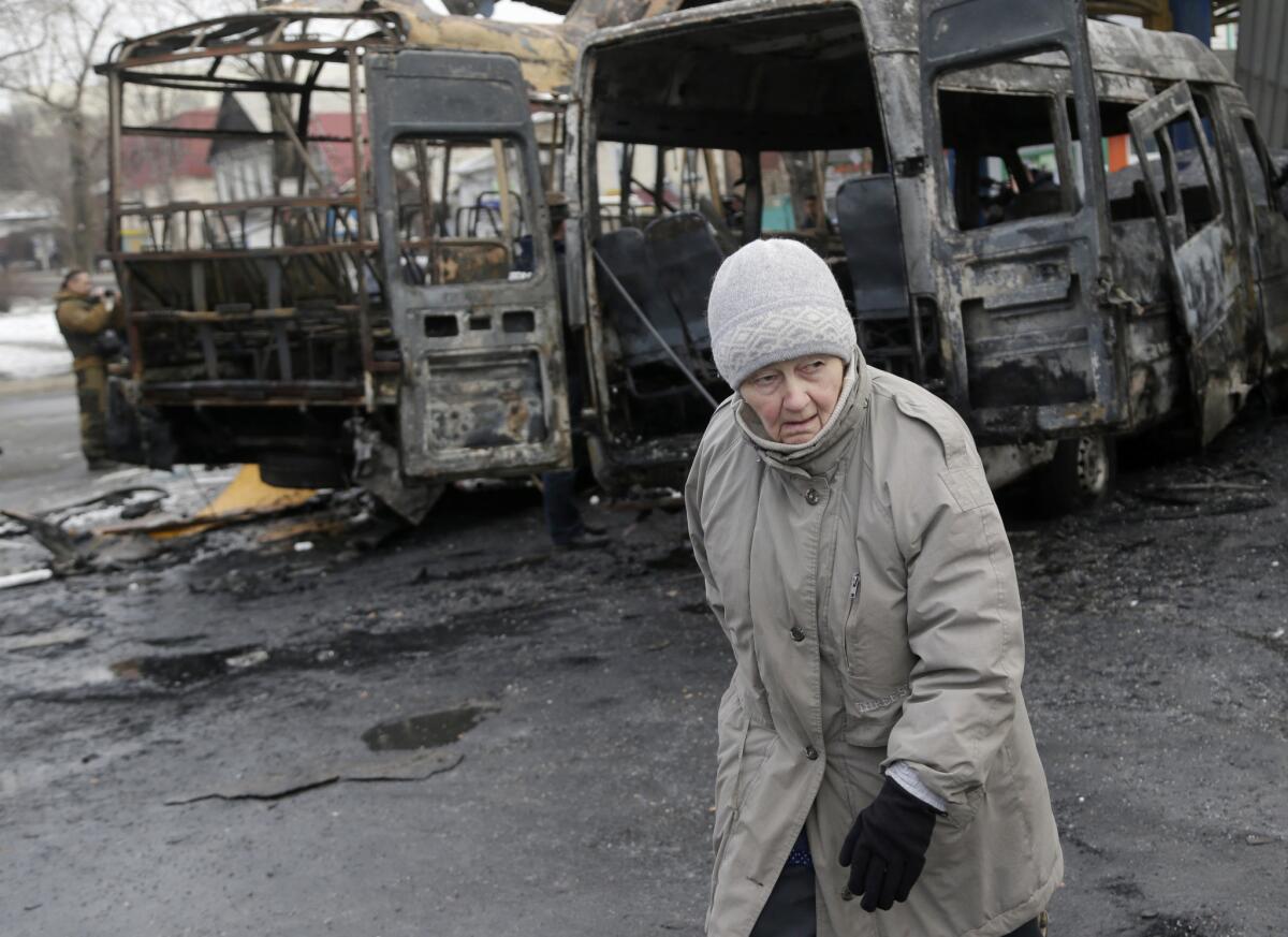 An woman walks past destroyed vehicles after a bus station was hit during fighting between Russian-backed separatists and Ukrainian government forces in Donetsk on Feb. 11.