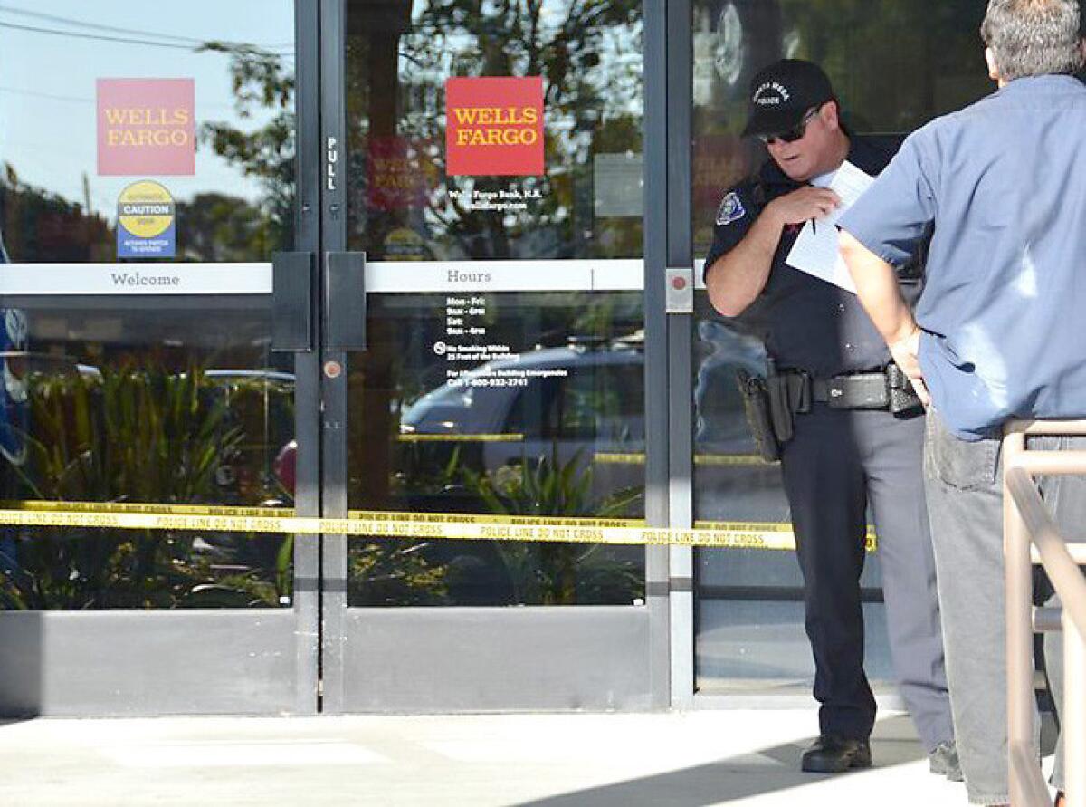 A Costa Mesa police officer surveys the entrance to the Wells Fargo bank at 301 E. 17th St., which was robbed Tuesday afternoon.