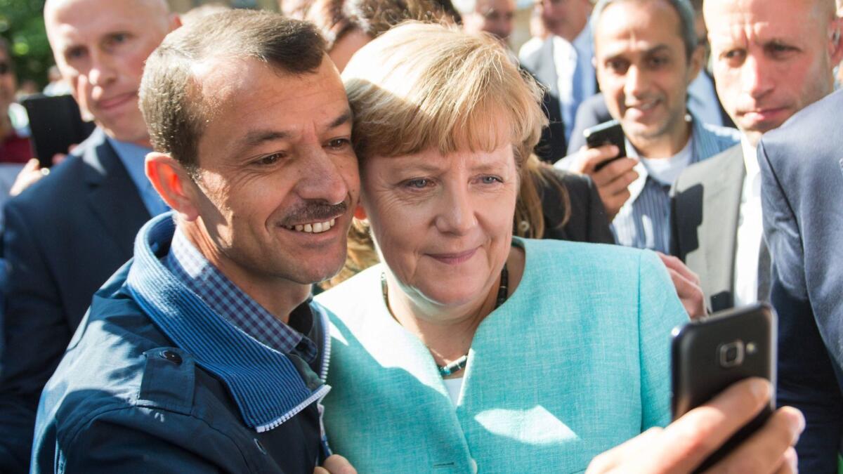 German Chancellor Angela Merkel, right, has a selfie taken with a refugee during a visit to a refugee reception center in Berlin on Sept. 10, 2015.