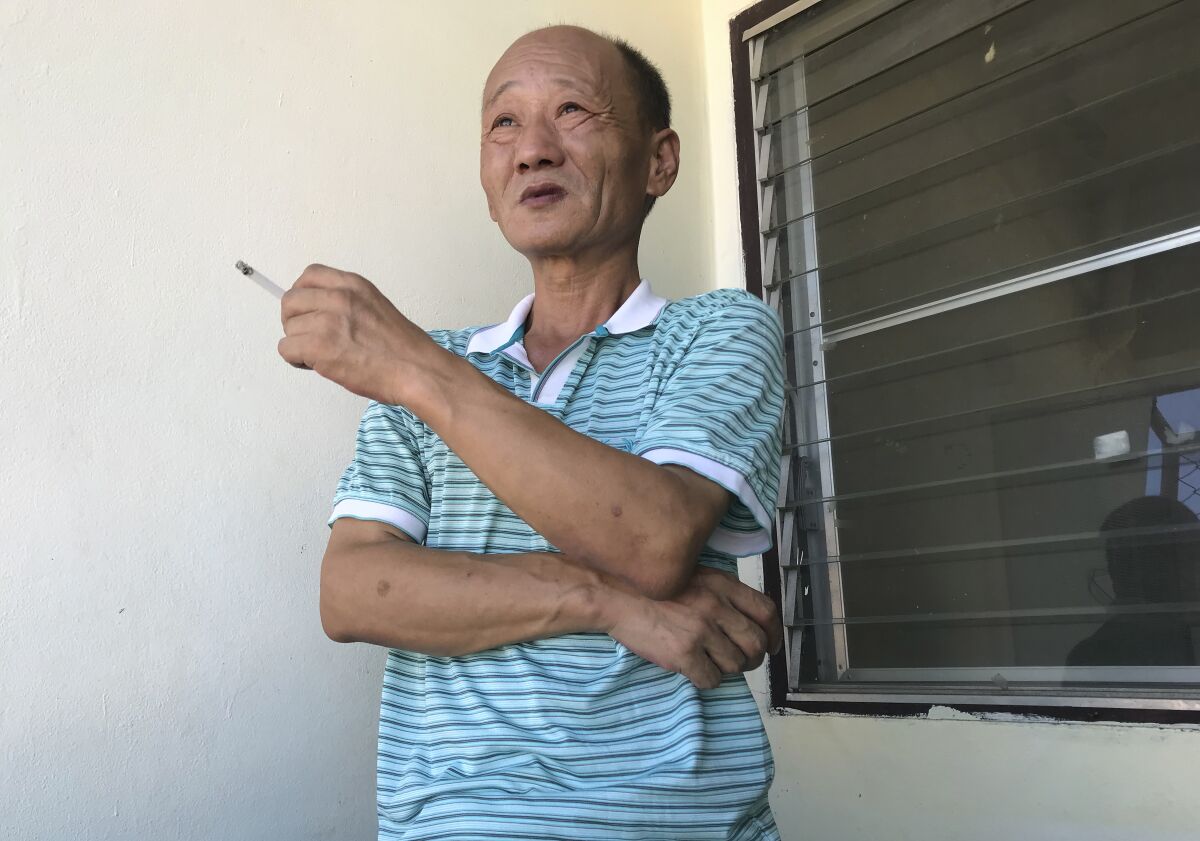 A man in a striped shirt smokes a cigarette. 