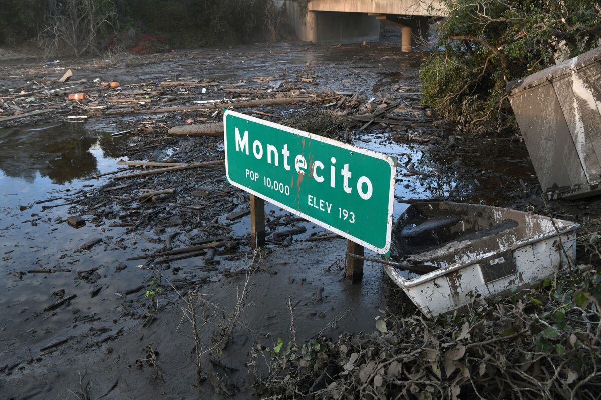 A Montecito freeway sign sits in mud on Highway 101. (Michael Owen)
