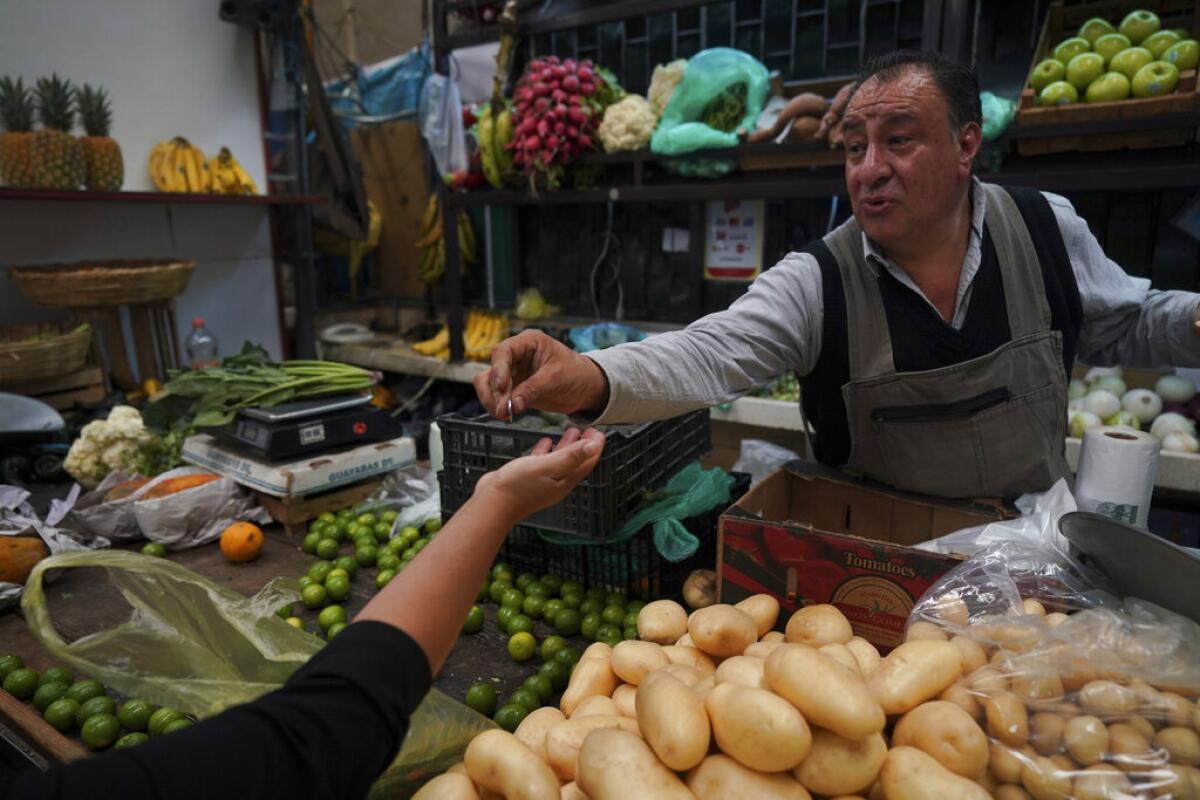 Un vendedor le da cambio a un cliente en el Mercado de Medellín,