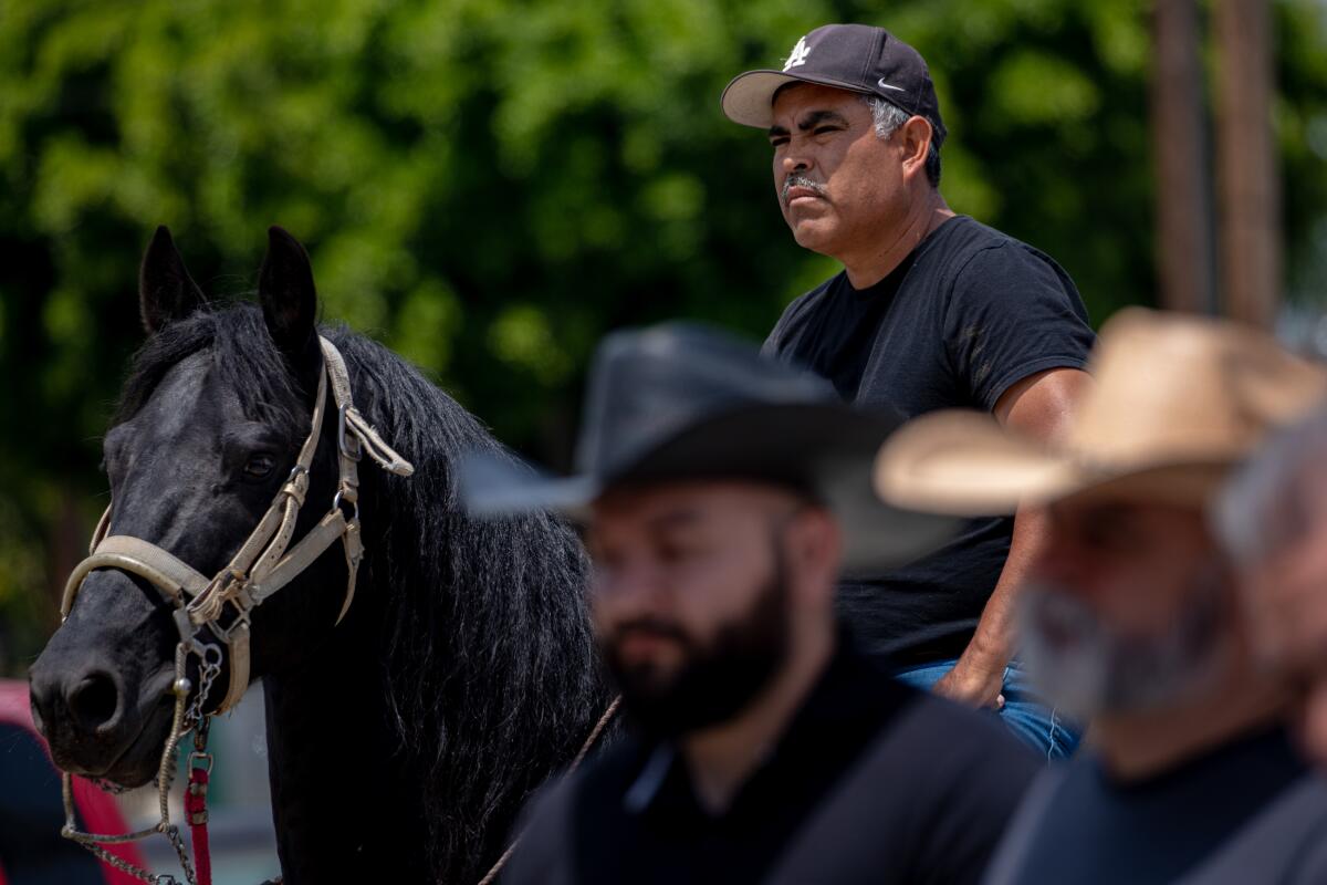 A man on a horse listens to a public meeting.
