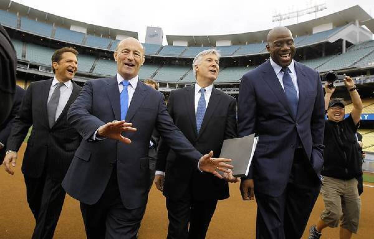 The new Dodger owners -- from left, Peter Guber, Stan Kasten, Mark Walter and Earvin "Magic" Johnson, are expected to get $6 billion-plus for the TV rights to their team's games.
