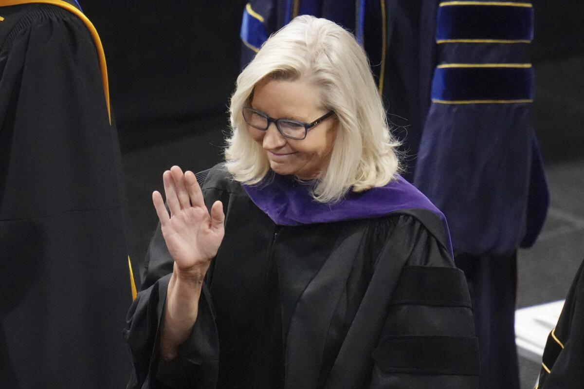 Liz Cheney in robes waves before delivering the commencement address.