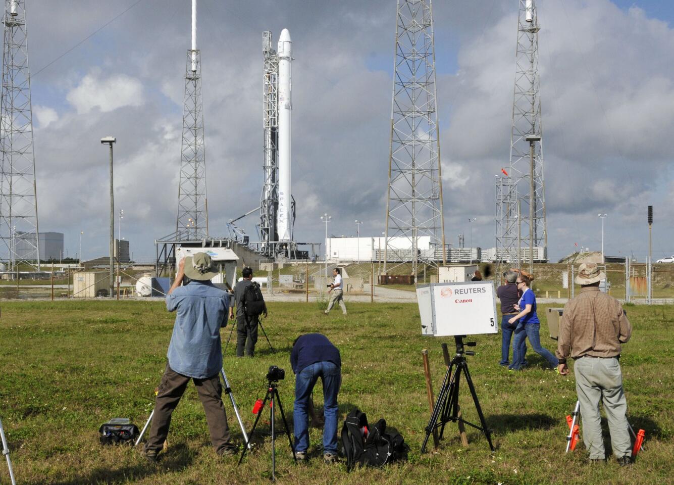 Photographers focus on SpaceX's Falcon 9 booster and unmanned Dragon cargo ship the day before the launch.