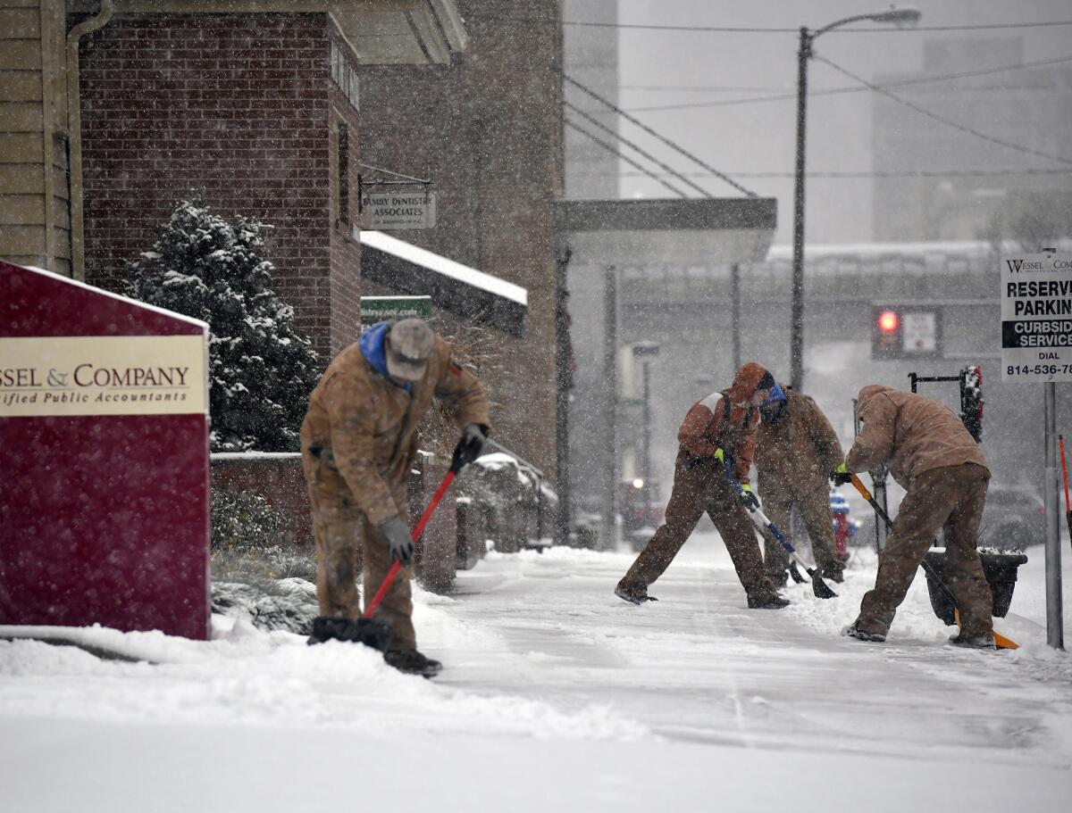 A crew from BZ Pools in Johnstown, Pa., work on shoveling the sidewalk