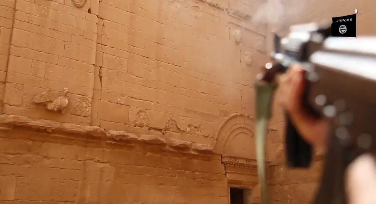 A militant fires his weapon at faces on a wall in Hatra, a fortified Iraqi city recognized as a UNESCO world heritage site.