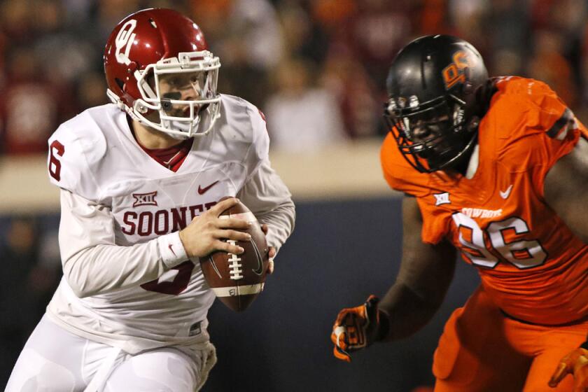 Oklahoma quarterback Baker Mayfield scrambles under pressure from Oklahoma State defensive tackle Vincent Taylor on Nov. 28.