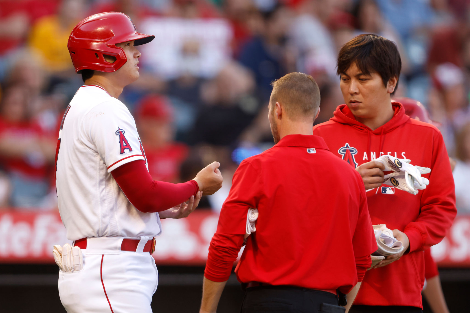 ngels star Shohei Ohtani talks to a team trainer, center, while with his translator.