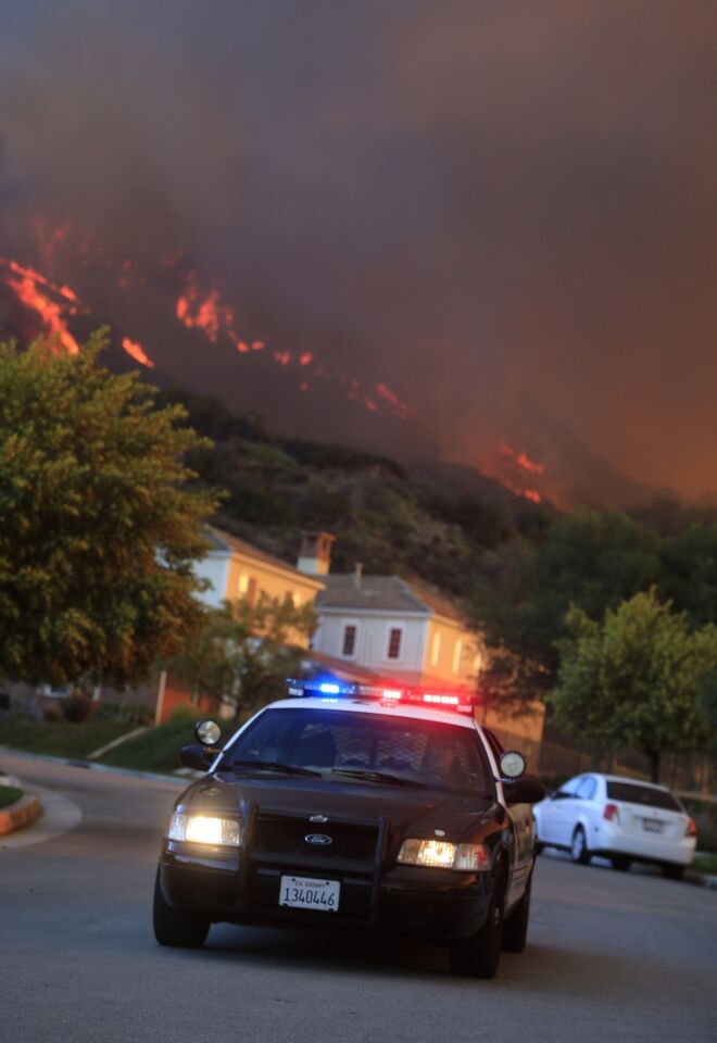 A police cruiser drives down Viewcrest Drive in Glendora urging residents to evacuate as the Colby fire burns in the Angeles National Forest.