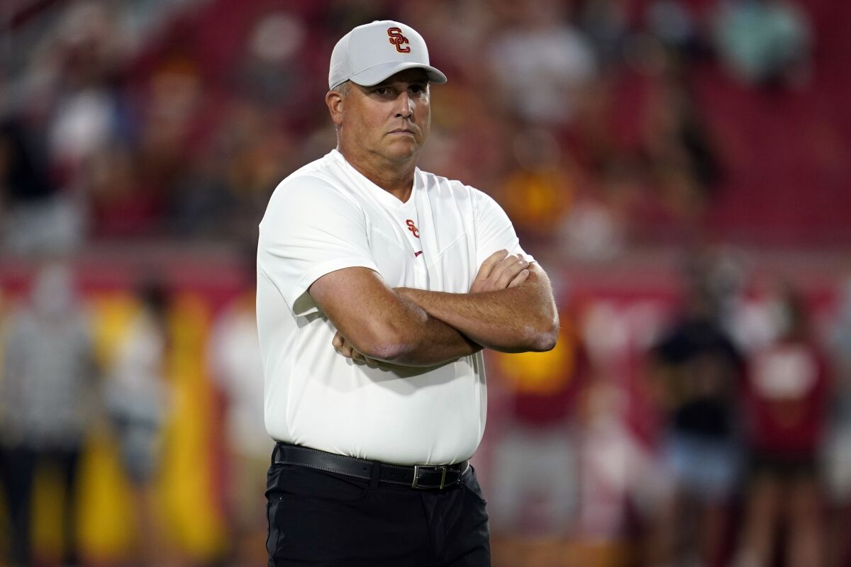 Clay Helton stands with arms crossed as he watches the Trojans warm up before the Stanford game.