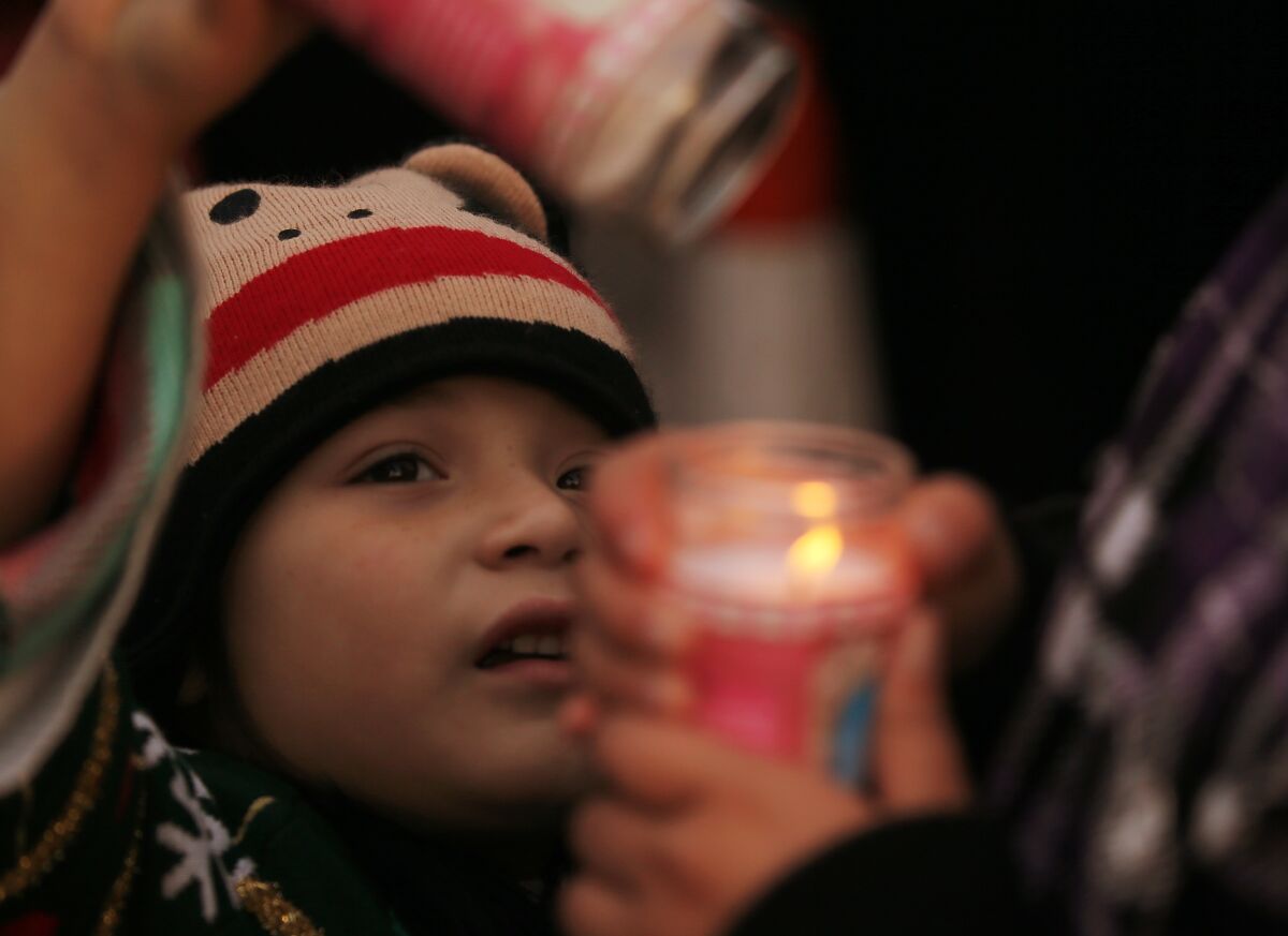 A child lights a candle during a vigil