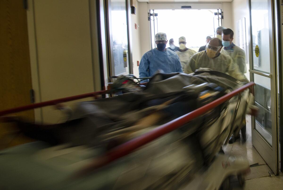 Emergency room staff move a patient to an exam area at a hospital