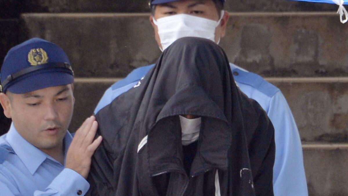 Officers escort murder suspect Kenneth Shinzato out of Uruma Police Station in Okinawa in May 2016.