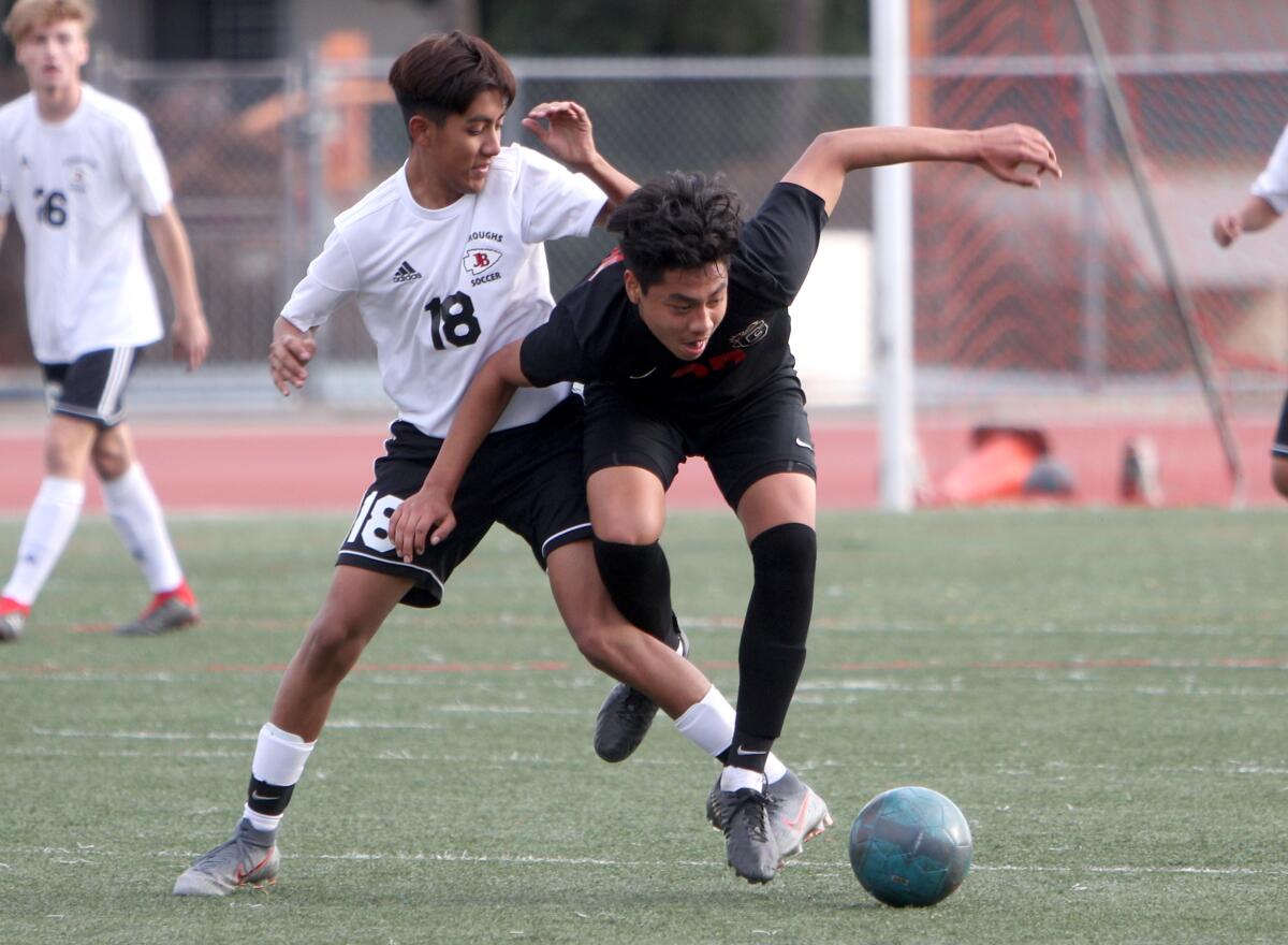 Glendale High School soccer player Bryant Santos gets tangled up with Patrick Abarca in game vs. Burroughs High at home in Glendale on Tuesday, Jan. 21, 2020.