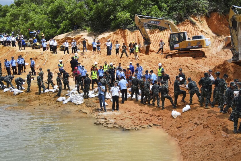 Rescuers work to build an embankment at the site of a flooded tunnel in Zhuhai in southern China's Guangdong Province, Thursday, July 15, 2021. Rescuers were pumping out water Thursday to try to find 14 construction workers trapped by a flood in a tunnel being built in southern China. The rescuers have not been able to contact the workers missing since the 3:30 a.m. flood, the Zhuhai city emergency management department said in an online post. (Chinatopix via AP)