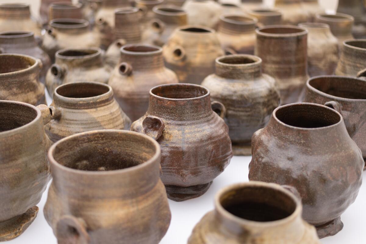 Earth-colored ceramic pots, each slightly different in shape and scale, with handles on either side.