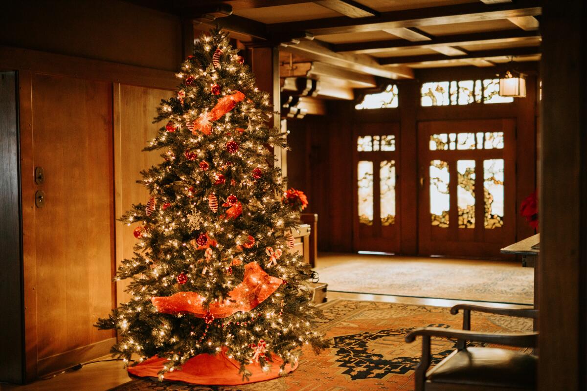 A decorated and lighted tree in a home with many sculptural wood accents.