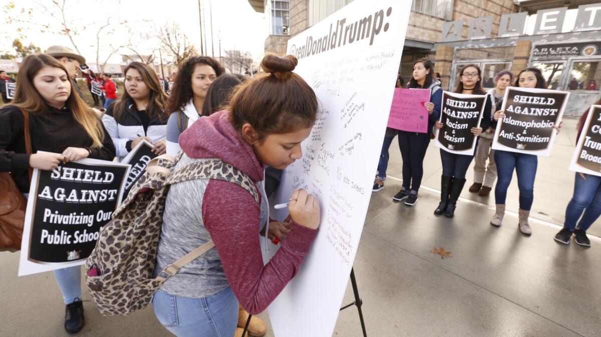 Arleta High School student Elizabeth Marquez, 15, signs her message on Thursday to Donald Trump for a "tweet storm." More than 100 students and teachers joined before classes to protest Trump's Friday inauguration.