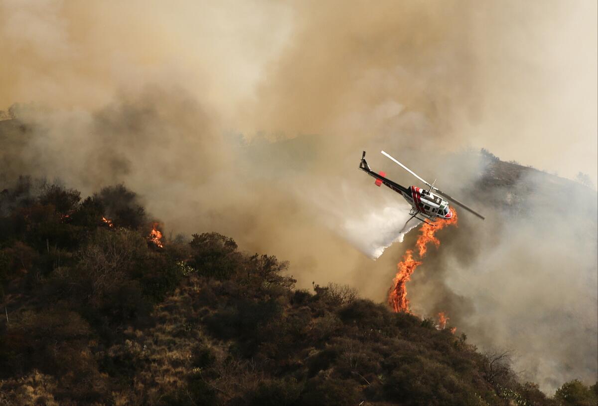 A helicopter drops water on the Colby fire above Azusa. The blaze has charred more than 1,900 acres.