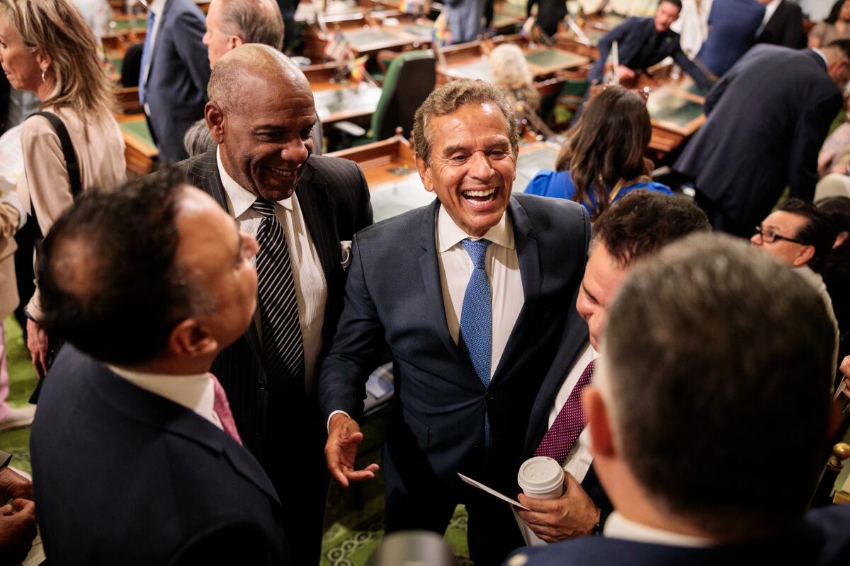 Men in suits and ties stand in a circle, laughing.
