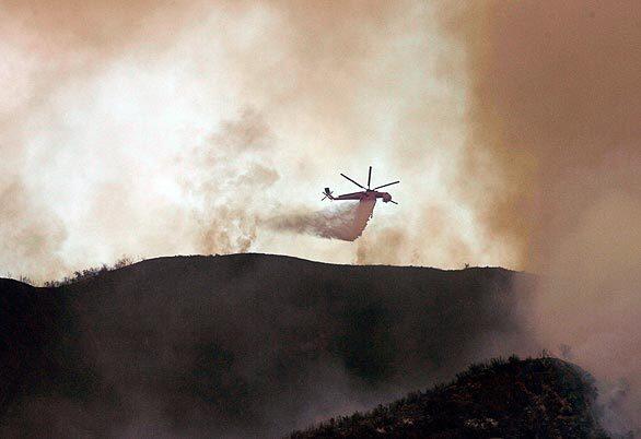 A helicopter drops water on the Morris fire.