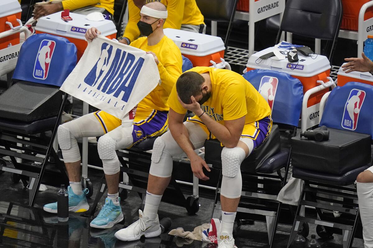 Lakers center Marc Gasol sits on the bench, bent over with his head in his hand
