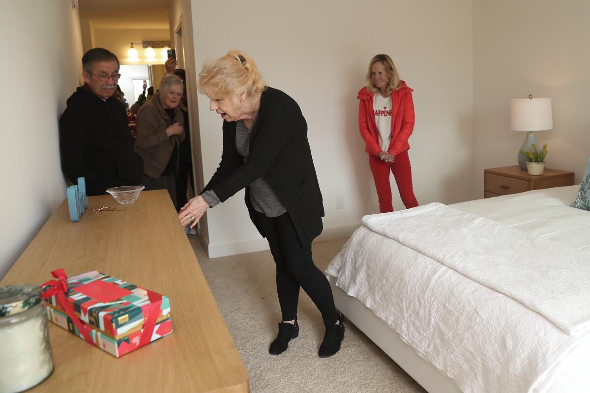 Judy Candelaria, center, admires her new bedroom dresser as she tours her new apartment on Thursday in Newport Beach.