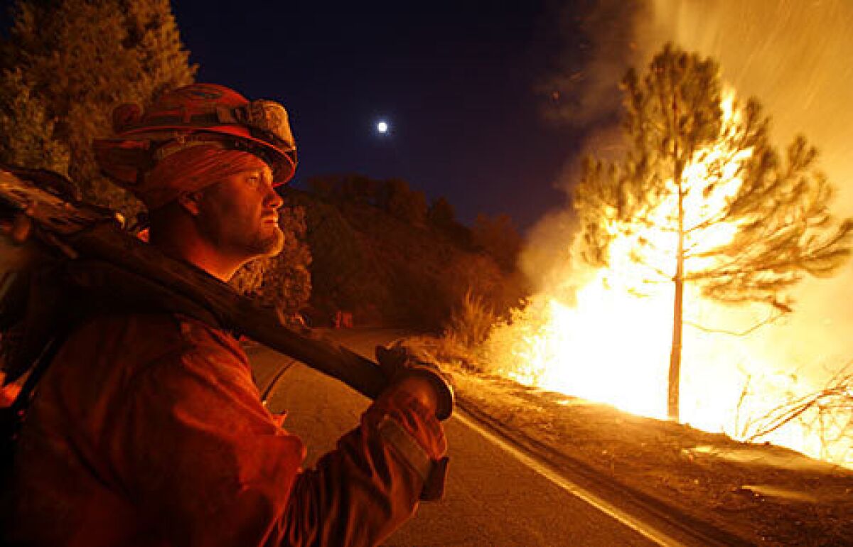 A firefighter watches a backfire burn off East Grade Road on Palomar Mountain after nightfall.