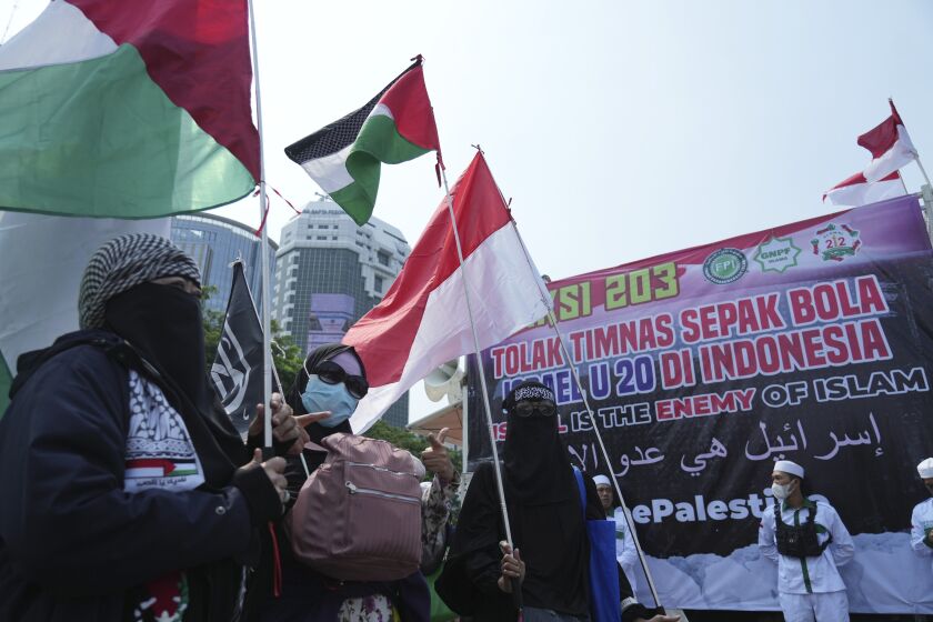 Protesters wave Palestinian flag during a protest in Jakarta, Indonesia, Monday, March 20, 2023. Hundreds of conservative Muslims have marched to the streets Monday in Indonesia's capital to protest against the Israeli team's participation in the FIFA World Cup Under-20 in Indonesia.(AP Photo/Achmad Ibrahim)