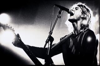 A black-and-white photo of Nirvan's Kurt Cobain performing onstage