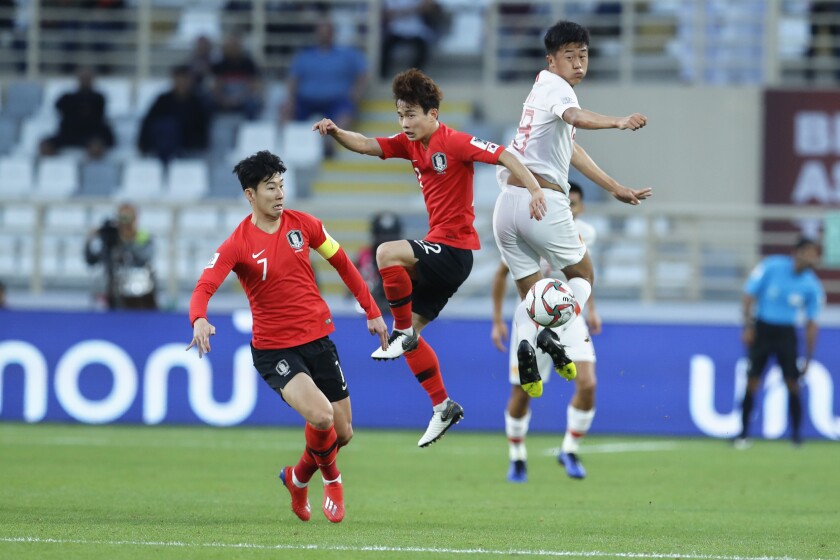 China's defender Liu Yang and South Korea's defender Kim Moon-Hwan jump for the ball.