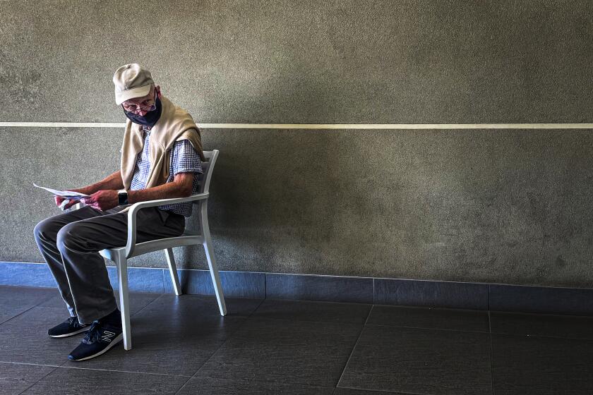 A lone man who was just tested for COVID-19 waits in line to make payment for the test at a private laboratory in Johannesburg, South Africa, Saturday Dec. 19, 2020. South Africa is bracing for its second wave, as many people will travel across provinces for vacations and visiting their families. (AP Photo/Jerome Delay)