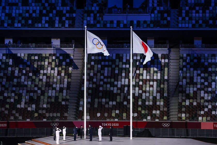 The Olympic flag is raised in front of empty seats at the Tokyo 2020 Olympics Opening Ceremony at Olympic Stadium.