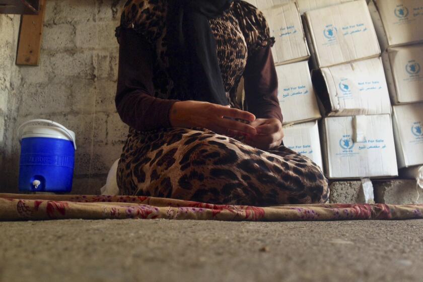 In this file photo taken Oct. 8, a 15-year-old Yazidi girl captured by the Islamic State group and forcibly married to a militant in Syria sits on the floor of a one-room house she now shares with her family in Maqluba, Iraq, after escaping in early August.