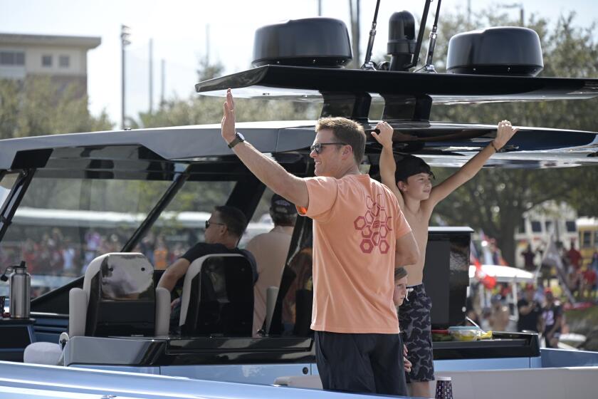 Tampa Bay Buccaneers quarterback Tom Brady waves to fans from his boat as his son Benjamin and daughter Vivian Lake stand next to him during a celebration of their Super Bowl 55 victory over the Kansas City Chiefs with a boat parade, Wednesday, Feb. 10, 2021, in Tampa, Fla. (AP Photo/Phelan M. Ebenhack)