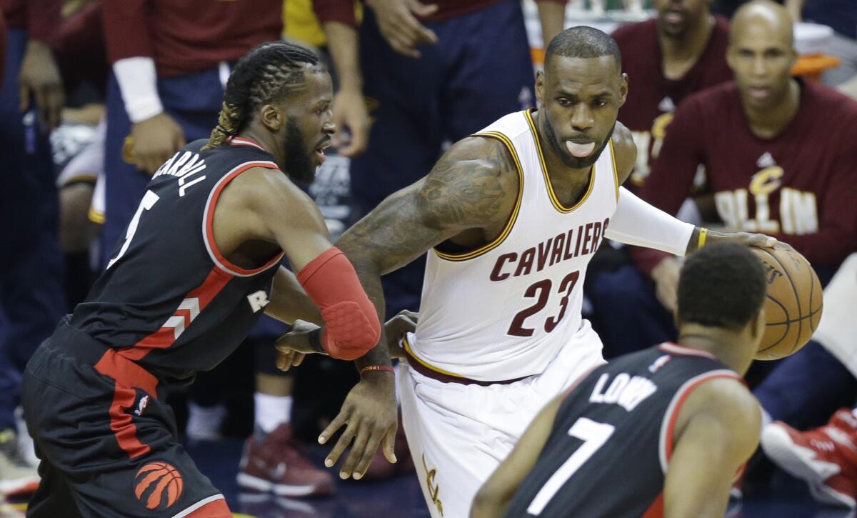 Cleveland Cavaliers' LeBron James (23) drives on Toronto Raptors' DeMarre Carroll (5) and Kyle Lowry (7) during the first half of Game 1 of the Eastern Conference finals on Tuesday.