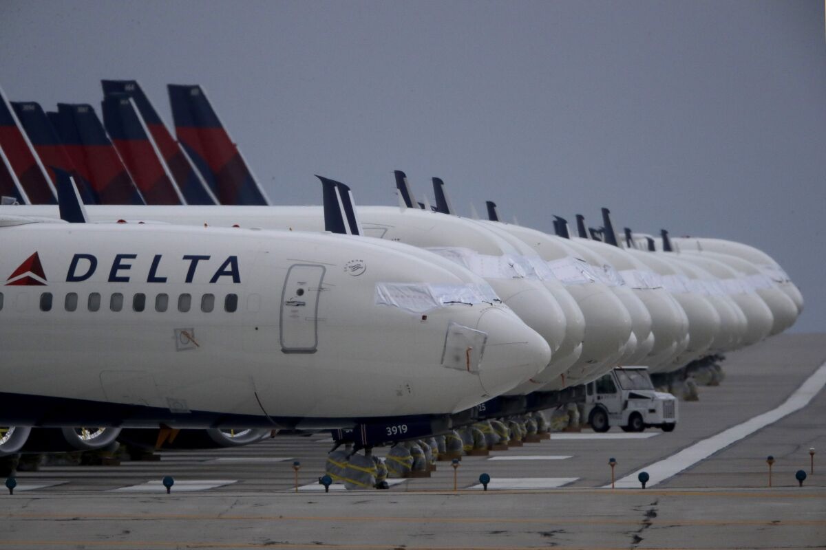 Several dozen mothballed Delta Air Lines jets are parked on a closed runway at Kansas City International Airport on Thursday, May 14, 2020 in Kansas City, Mo. Delta Air Lines said Monday, Aug. 31, 2020 that it will drop the fee for domestic flights. Delta is following the example set by United Airlines and saying it will drop an unpopular $200 fee on customers who change a ticket for travel within the United States. The moves come as airlines are desperately trying to lure people back to flying. (AP Photo/Charlie Riedel)