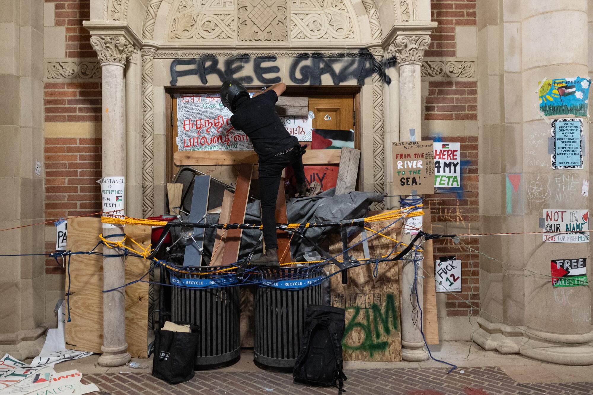 A person climbs some stuff under graffiti that says "Free Gaza."