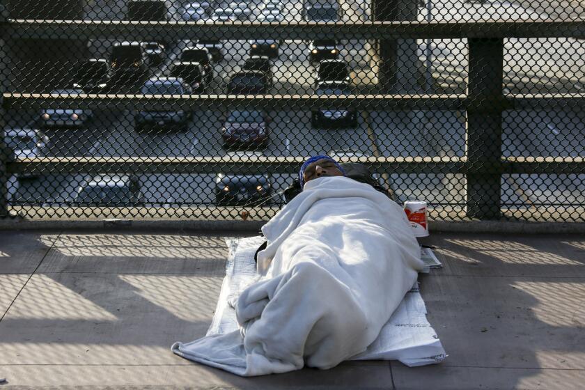 A homeless man sleeps on the Main Street bridge in downtown Los Angeles.