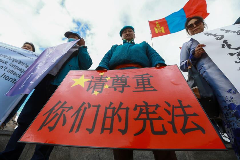 A Mongolian man holds a protest banner in the shape of the Chinese flag which reads "Respect your constitution" during a protest against China's plan to introduce Mandarin-only classes at schools in the Chinese province of Inner Mongolia, at Sukhbaatar Square in Ulaanbaatar, the capital of Mongolia on September 15, 2020. - Protests greeted Chinese Foreign Minister Wang Yi on a visit to Ulaanbator on September 15, with around a hundred Mongolians gathered in the city's main square to speak out against the Chinese government and its new language policy. (Photo by BYAMBASUREN BYAMBA-OCHIR / AFP) (Photo by BYAMBASUREN BYAMBA-OCHIR/AFP via Getty Images)