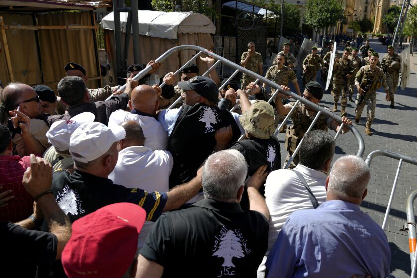 Fuerzas militares riñen con jubilados del ejército que intentan ingresar al edificio del Parlamento durante una sesión de los legisladores sobre el presupuesto de 2022, en una protesta en el centro de Beirut, Líbano, el lunes 26 de septiembre de 2022. (AP Foto/Bilal Hussein)