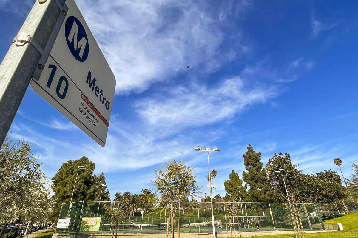 A Metro 10 bus sign in front of tennis courts