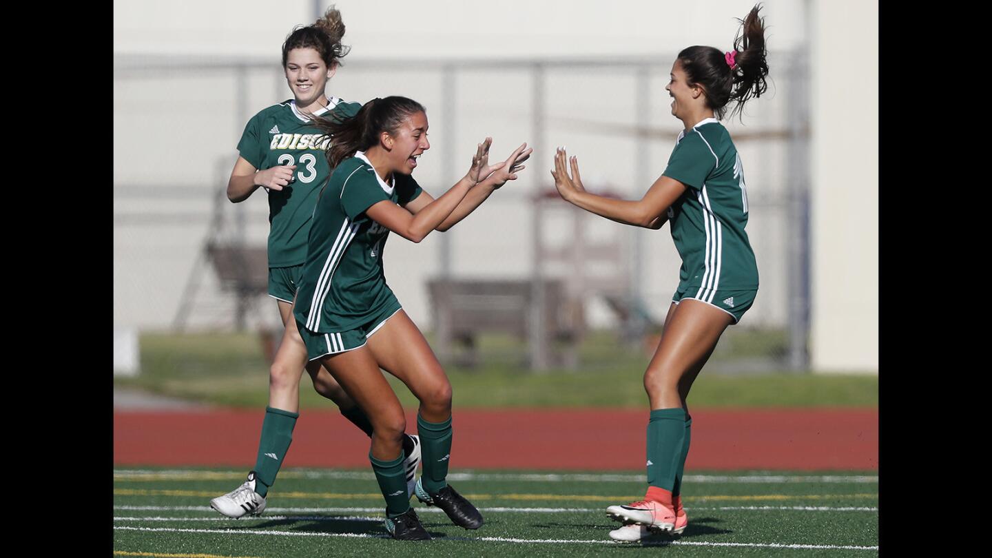 Edison High's Cecelia Roghair, center, celebrates a goal with teammate Rachelle Elve, right, during the first half against Fountain Valley in a Sunset League girls' soccer game on Tuesday. Roghair made the assist to Elve to give the Chargers a 1-0 lead.
